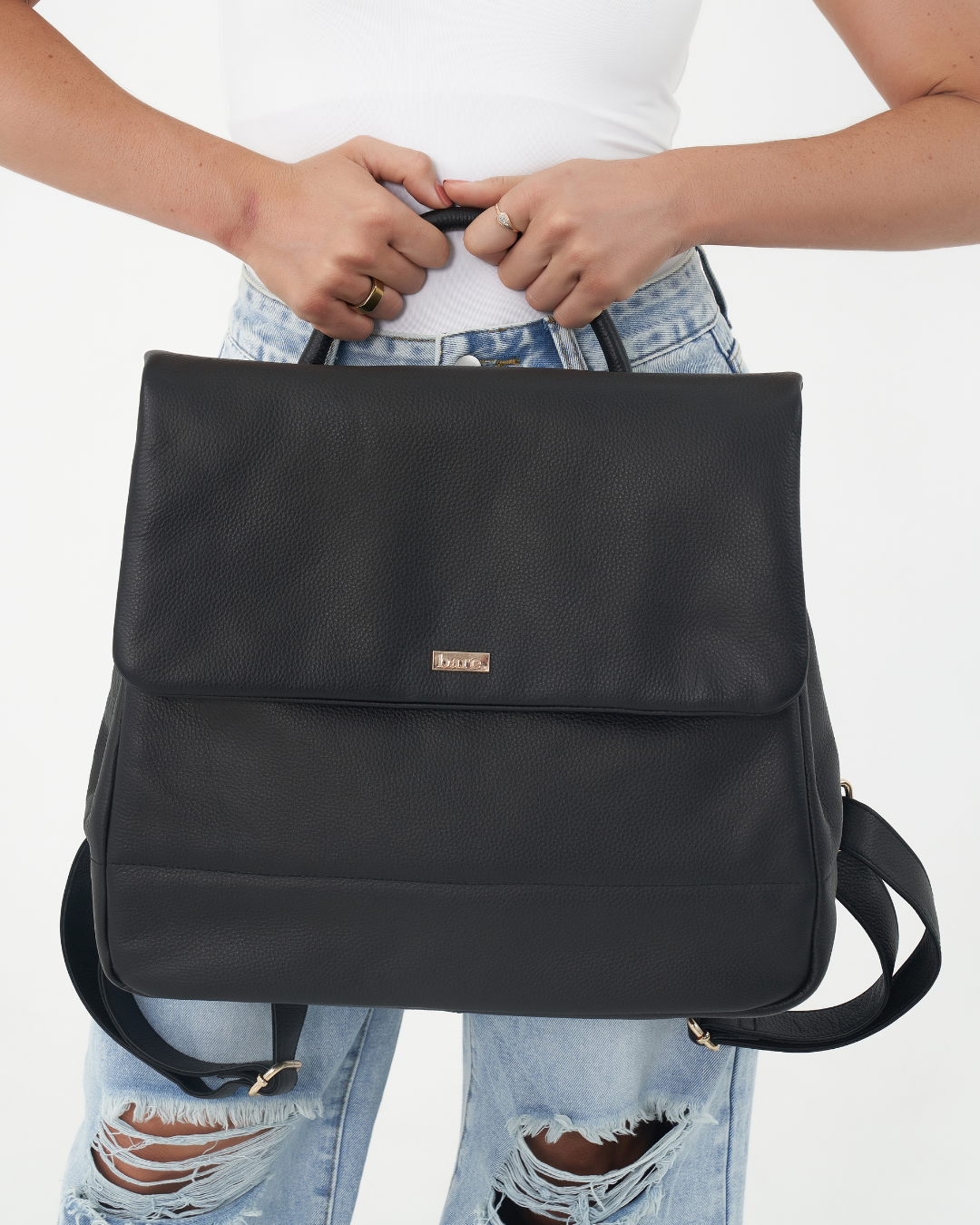Model holding Black Bare Leather Lottie Backpack. Front