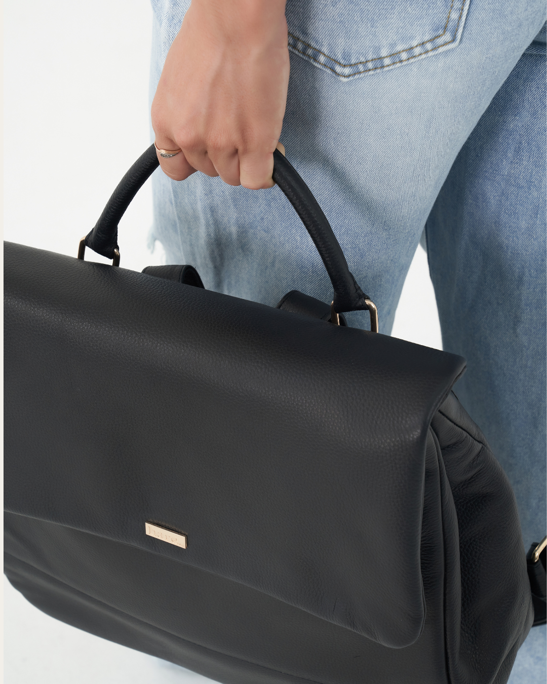 Model holding Black Bare Leather Lottie Backpack by the handle. Front
