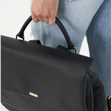 Model holding Black Bare Leather Lottie Backpack by the handle. Front