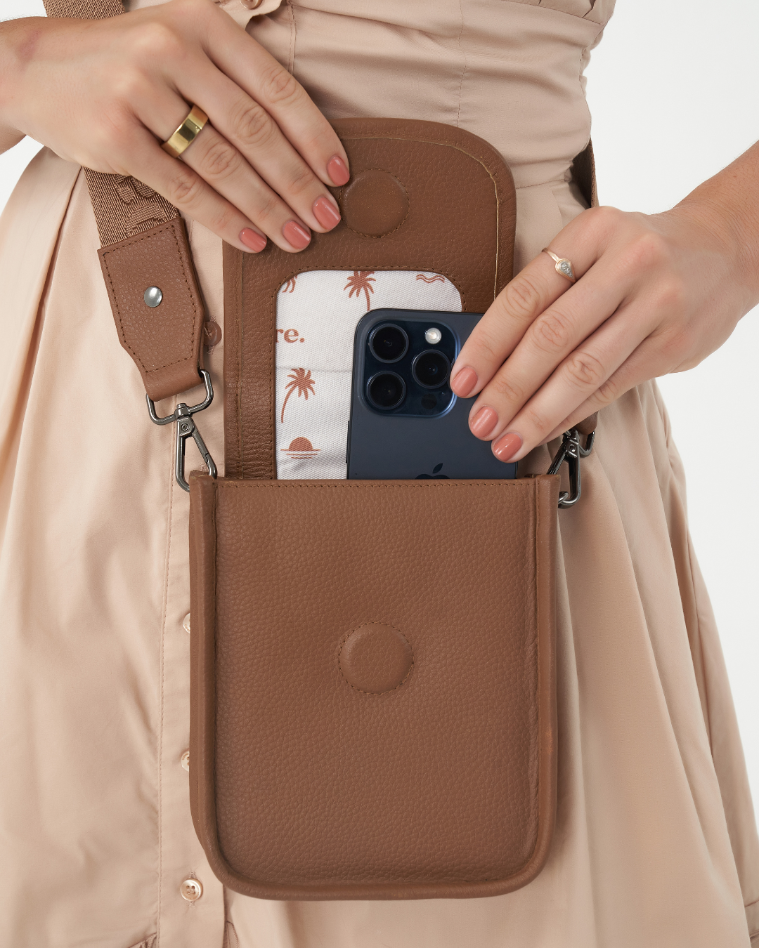 Model wearing Camel Bare Leather Hadley bag. Model is showing a phone in the bag. Front