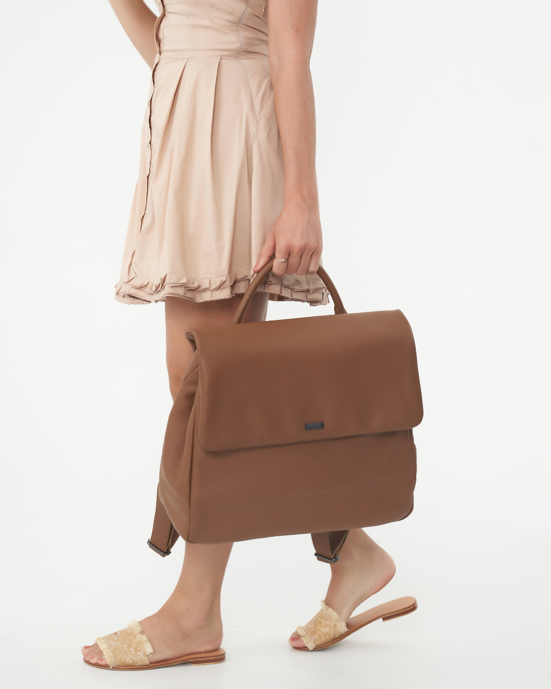 Model holding Camel Bare Leather Lottie Backpack at her side. Front