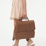 Model holding Camel Bare Leather Lottie Backpack at her side. Front