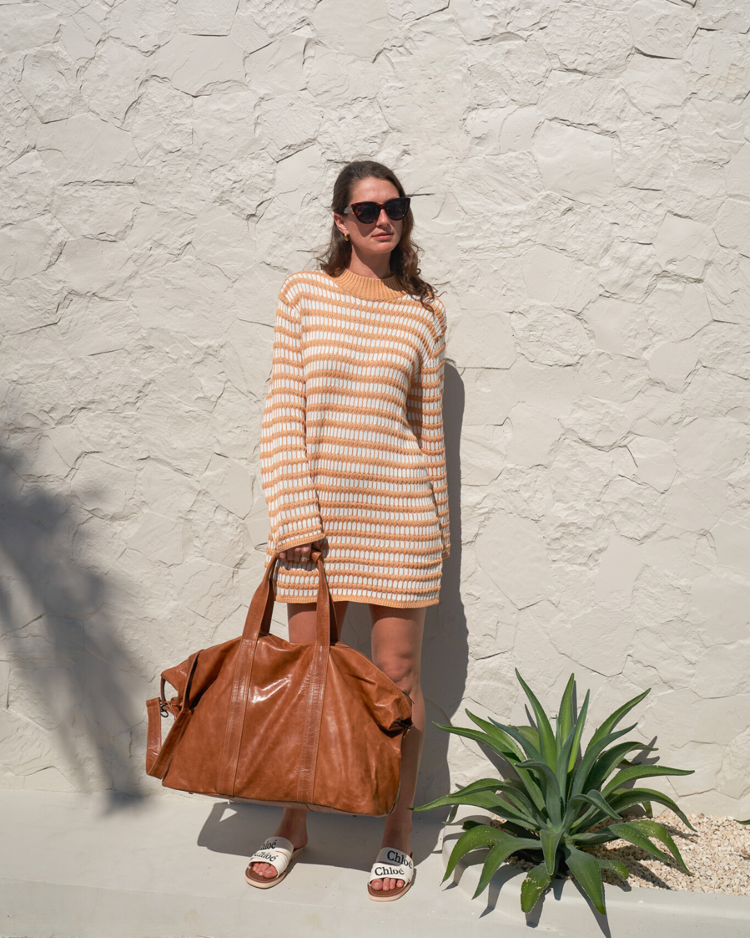 Model holding Camel Bare Leather Travel Bag by the straps. Front