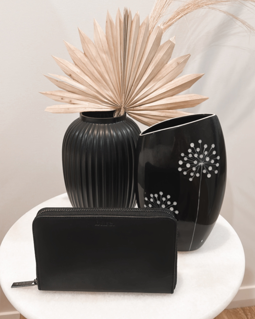 Black Bare Leather Quinn wallet displayed on a table. Front