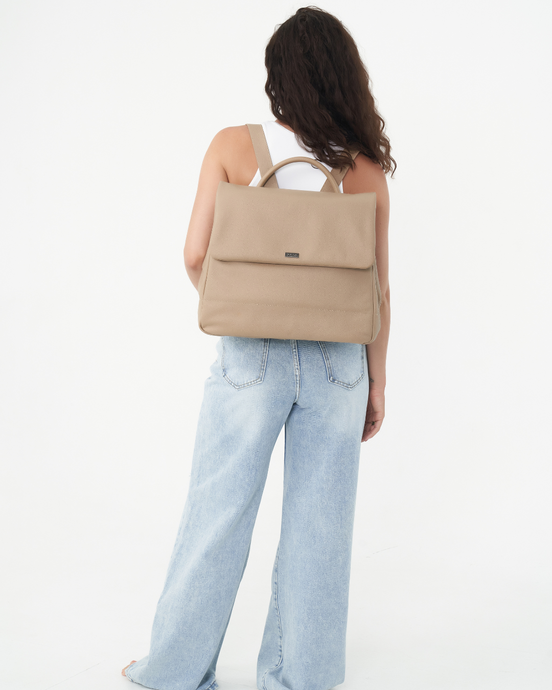 Model with the Stone Bare Leather Lottie Backpack on her back. Front