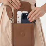 Model wearing Camel Bare Leather Hadley bag. Model is showing a phone in the bag. Front