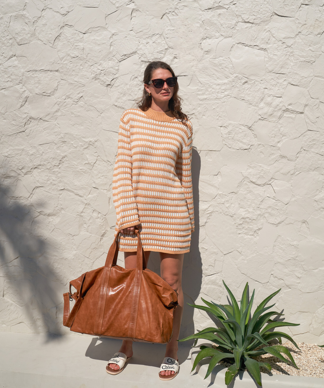 Model holding Camel Bare Leather Travel Bag by the straps. Front