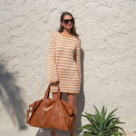 Model holding Camel Bare Leather Travel Bag by the straps. Front