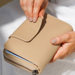 Image of model holding a stone bare leather Jorja Wallet 